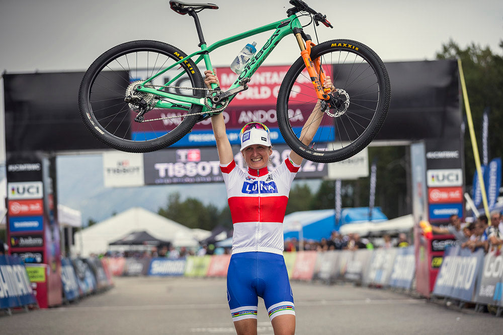 Catharine holding her bike above her head while rocking the World Cup leaders jersey.